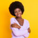 woman with afro against yellow background hugging self