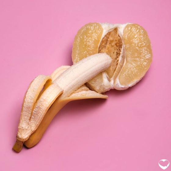 A peeled banana tip lying on on a half-cut orange