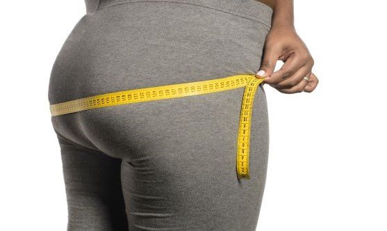 woman measuring her ass diameter with tape measure