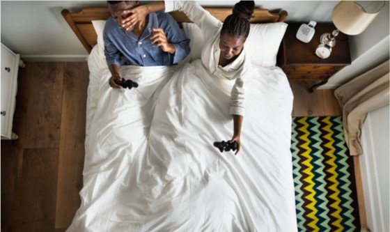 Playful couple in bed with their phones 