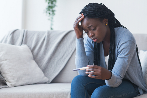 stressed woman staring at a pregnancy test