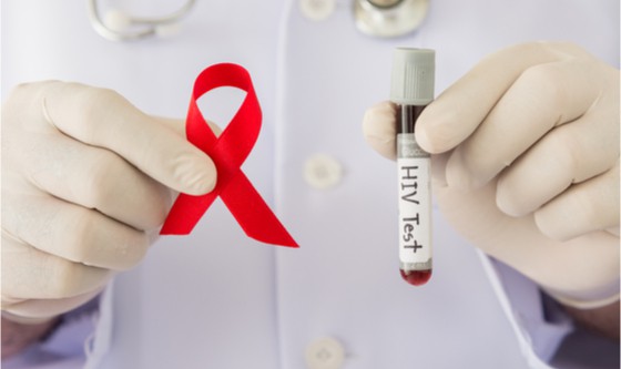 Health care professional holding a test tube and an AIDS ribbon 