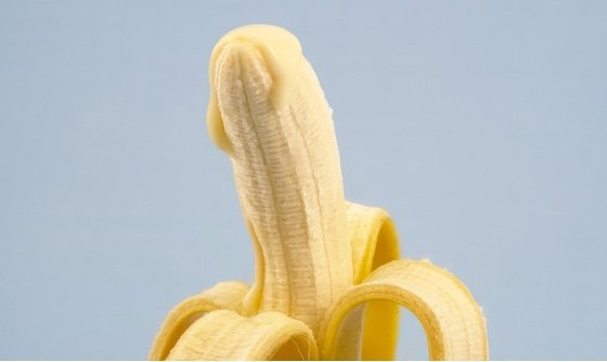 A halfway peeled banana with creamy liquid coming from the tip