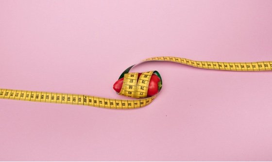 A red bell pepper surrounded by a tape measure twice