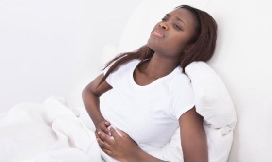 woman in pain learning over the headboard