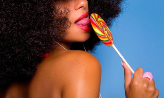 woman licking a rainbow lollipop