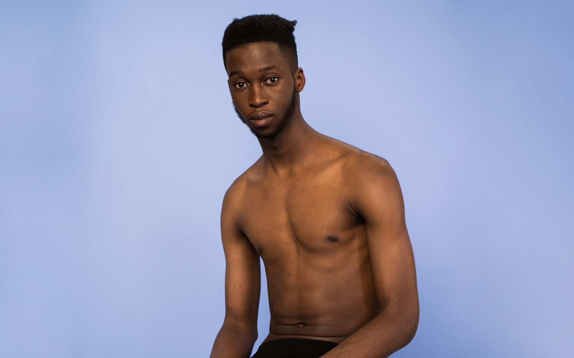 Man with bare torso in front of blue background 