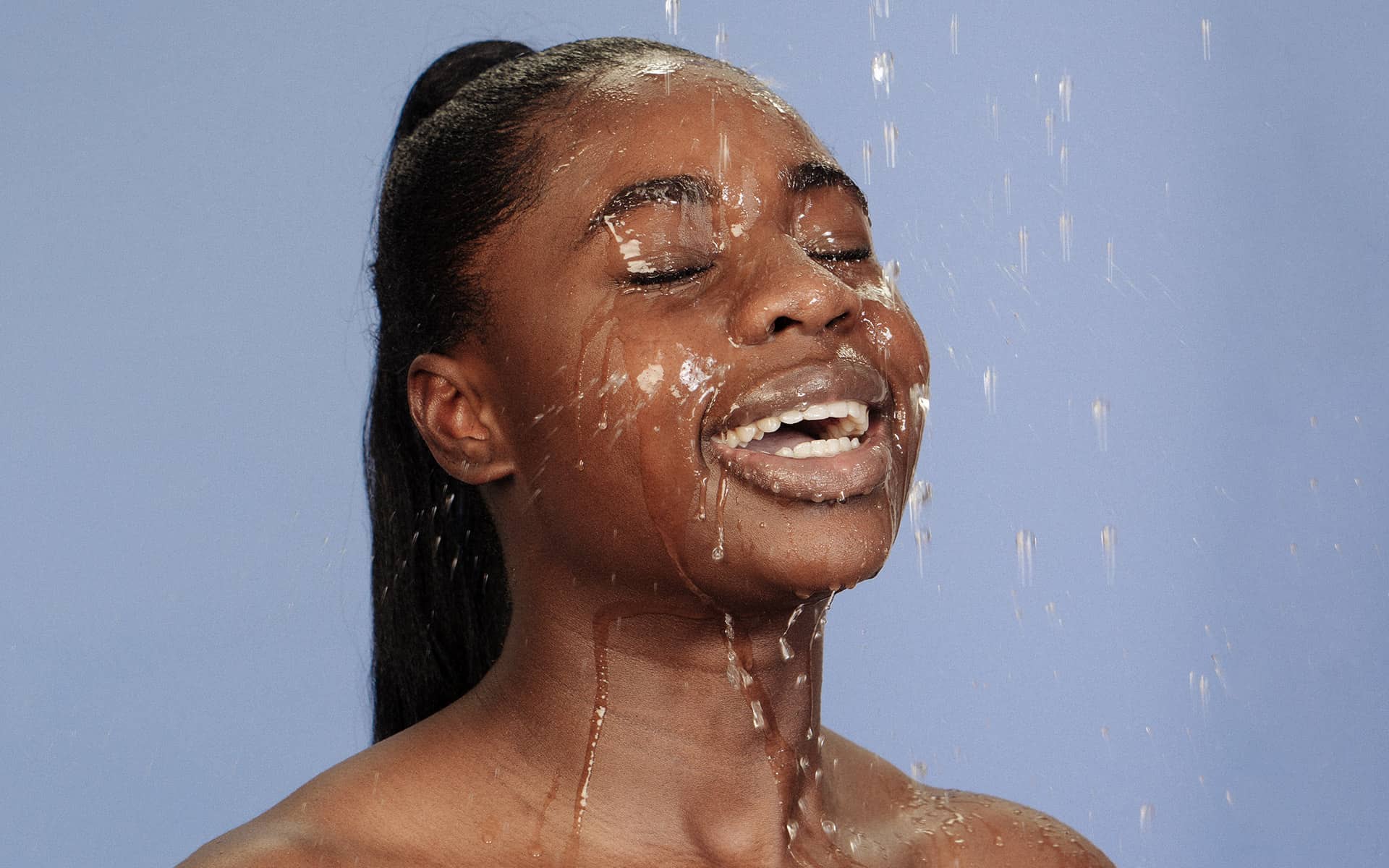 Woman with water on her face as if she is in the shower 