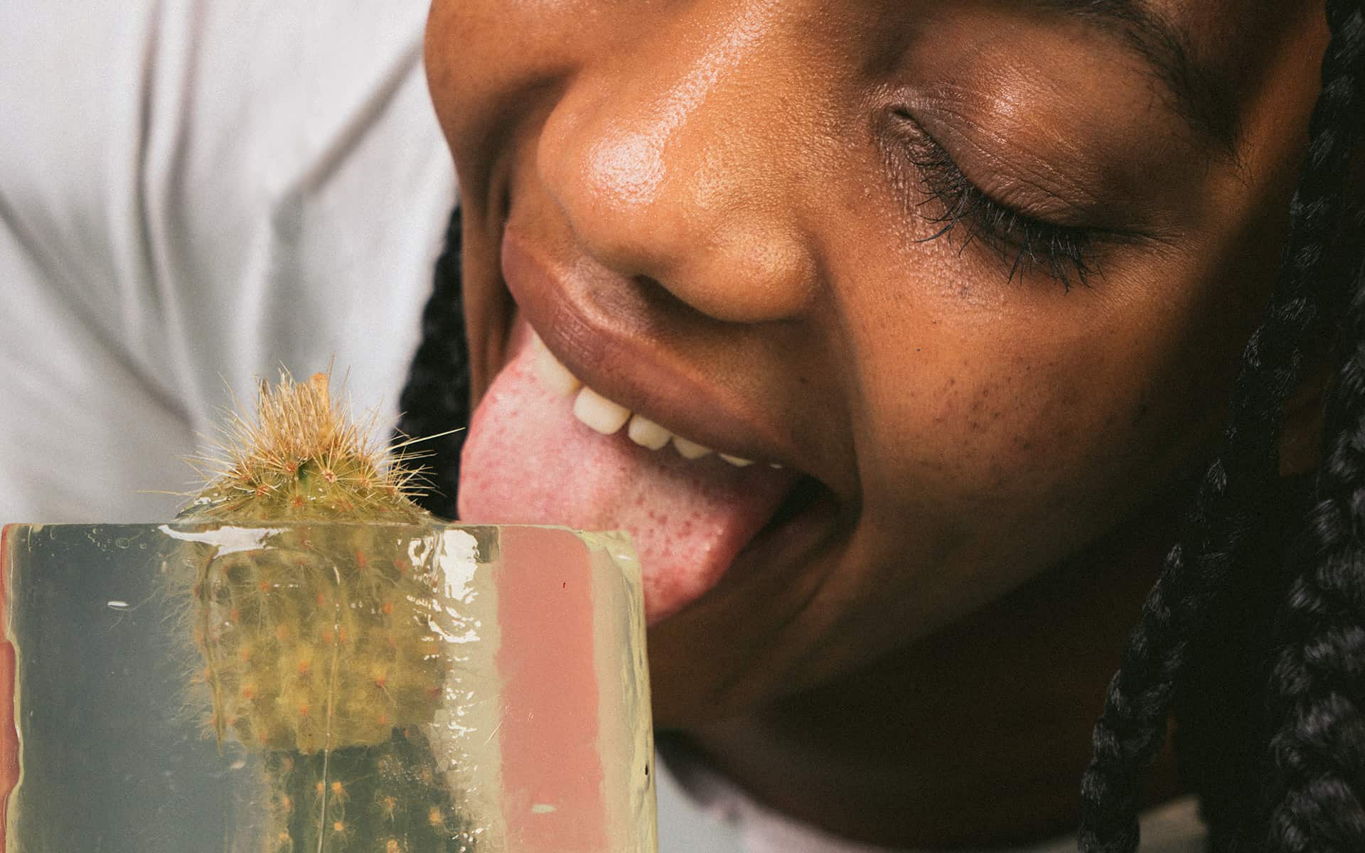 Woman licking ice-cube containing a phallic cactus 