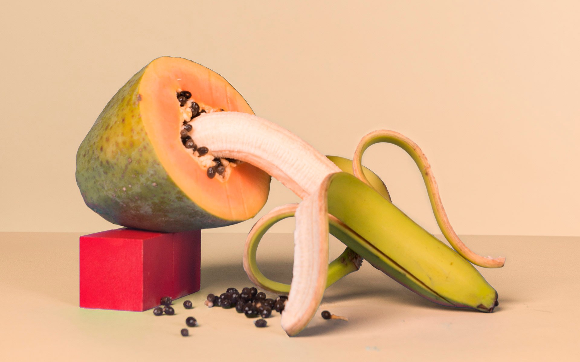 The tip of a banana going into a pawpaw fruit