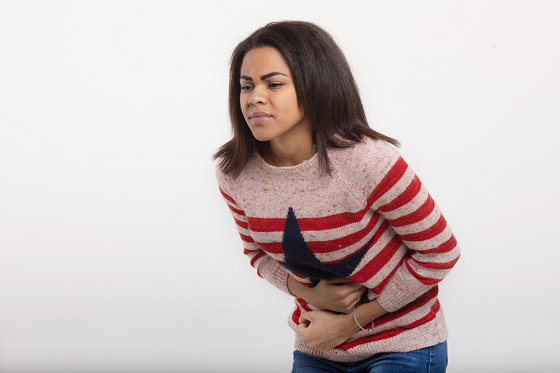 woman in pain bending as she holds her stomach