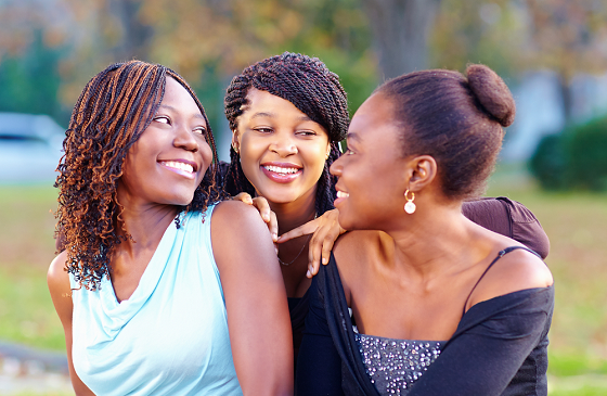 Three girls looking at each other smiling 