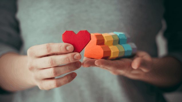 Hands holding rainbow paper hearts, LGBT symbol