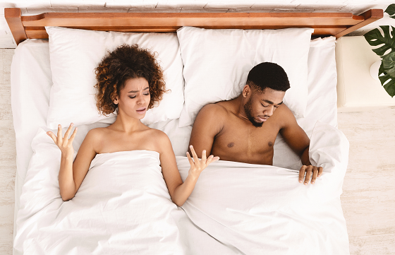 man and woman in bed with half body covered in white sheets