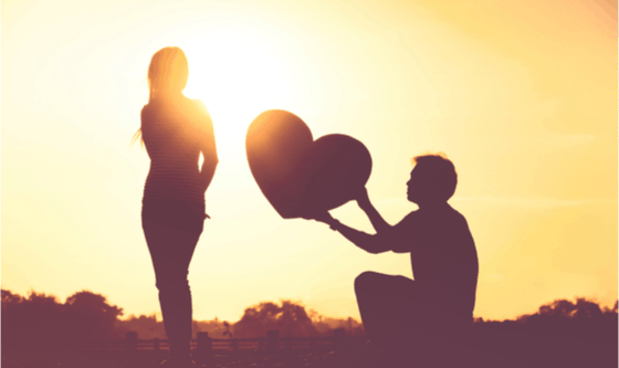 Man handing woman a heart at sunsnet