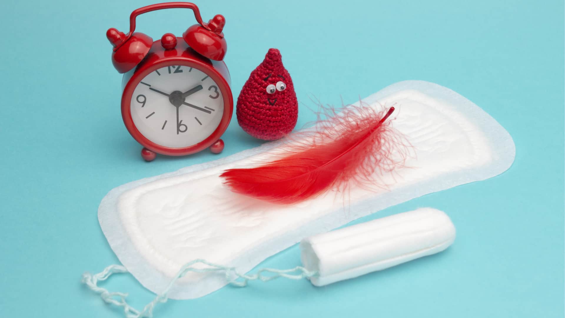 Red dreamy smile crochet blood drop, daily and menstrual pad and tampon on blue background.