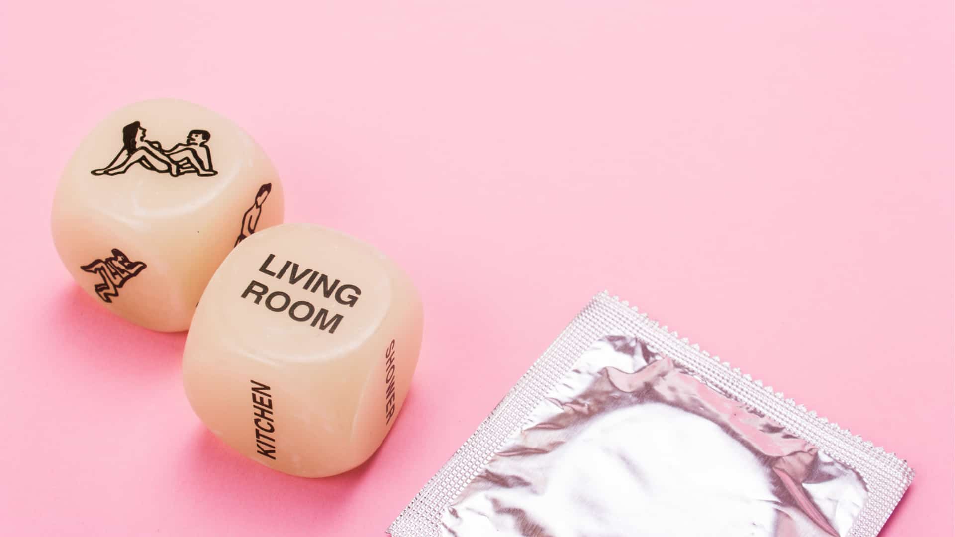 condom and custom dice with sex positions in pink background