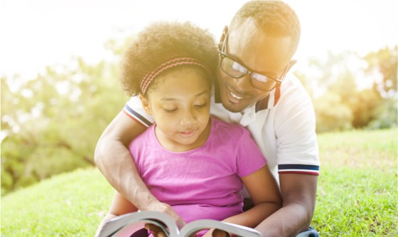 man teaching reading a book with his daughter 