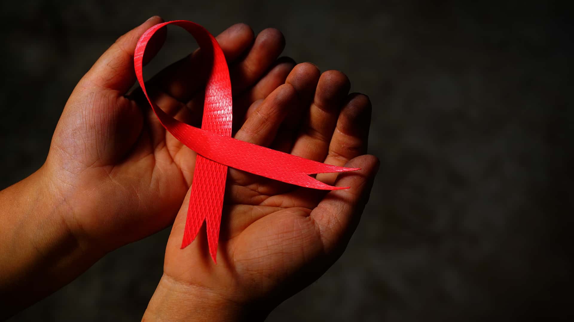 red aids ribbon in hand.