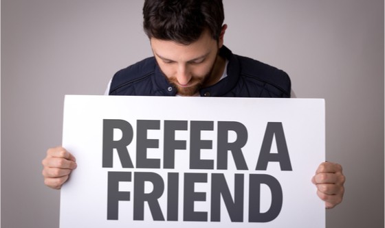 Man holding up a 'refer a friend' sign
