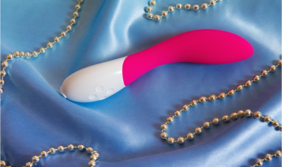 White and pink vibrator on blue silk with pearl necklace