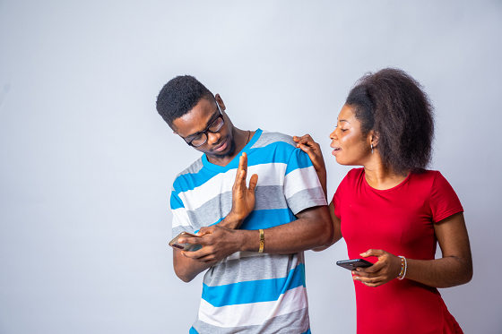 man using had sign to forbid woman from checking his phone