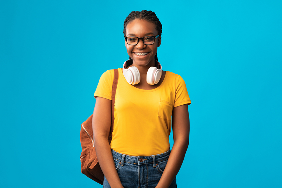 Young adolescent carrying white bag and wearing white earphones around her neck