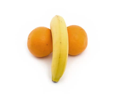 ripe banana with one side between two ripe oranges