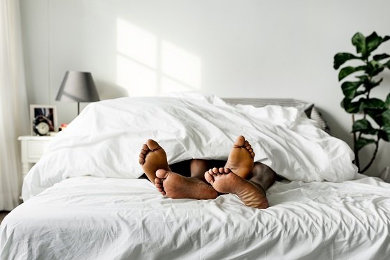 two pairs of feet on edge of bed