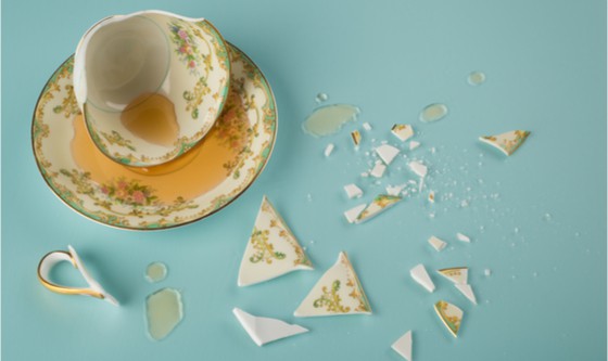 Broken tea cup with spilled tea and shards