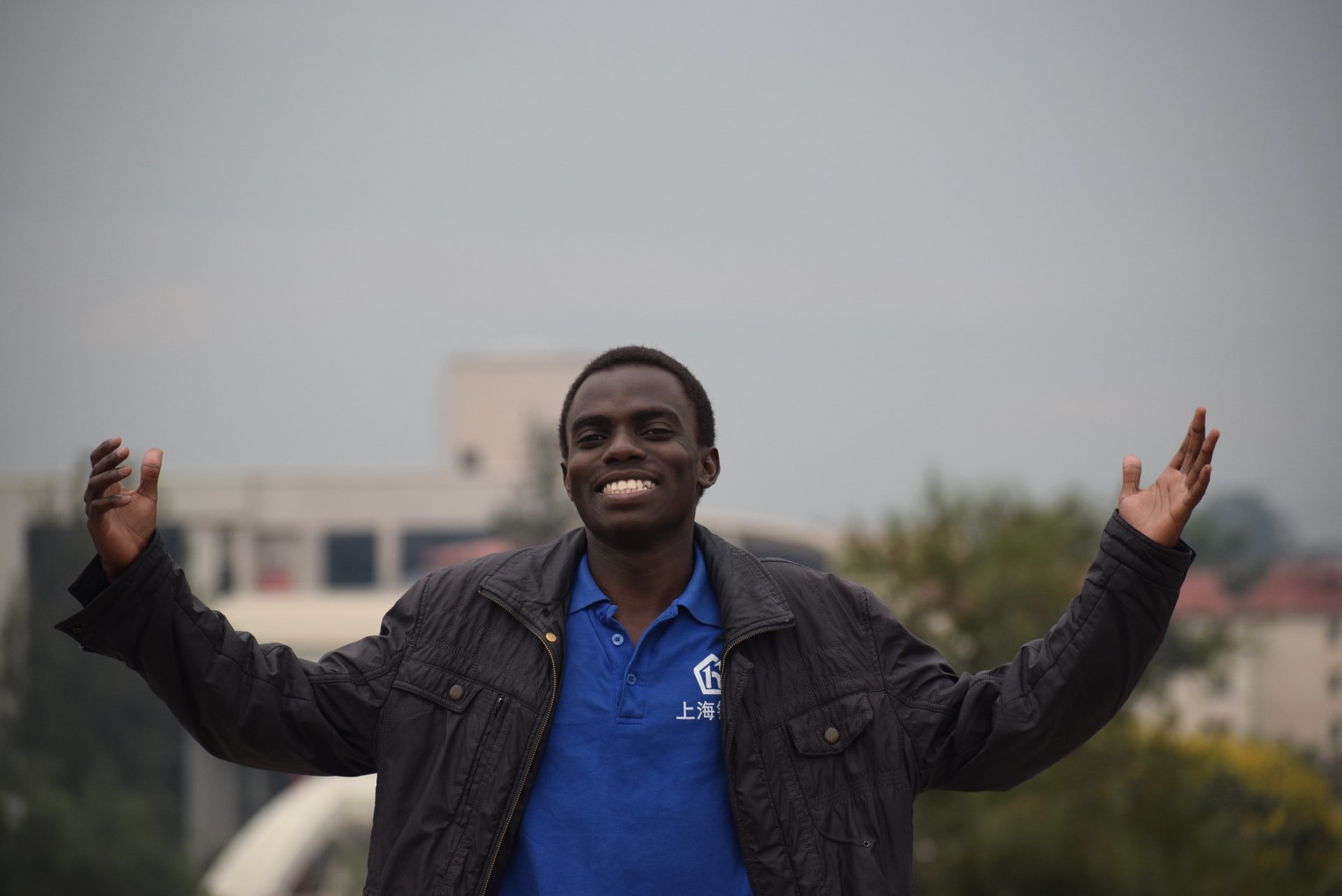 A young black man with his arms spread, smiling at the camera