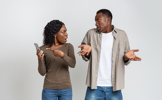 woman angry at a man as she points to phone 