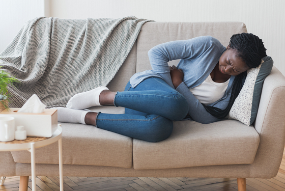 women in pain coiling herself on a sofa