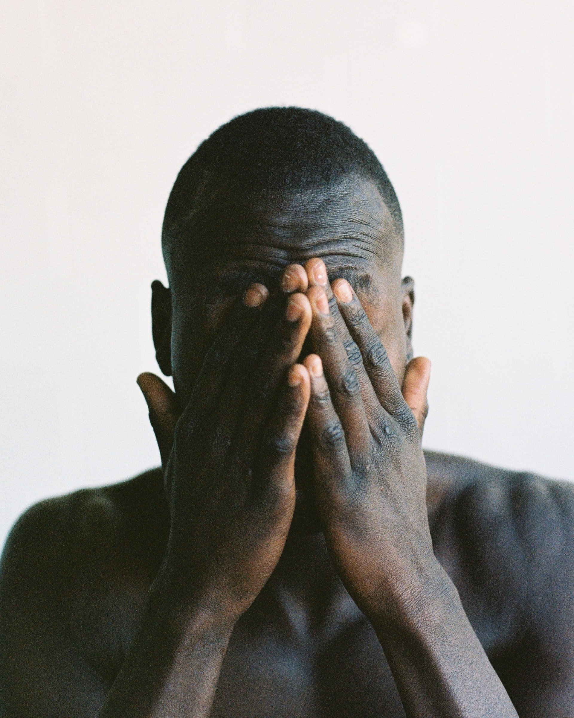 A black man holding his hands to his forehead