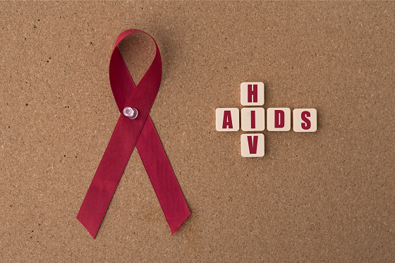 Red ribbon alongside a chips cross bearing HIV/AIDS