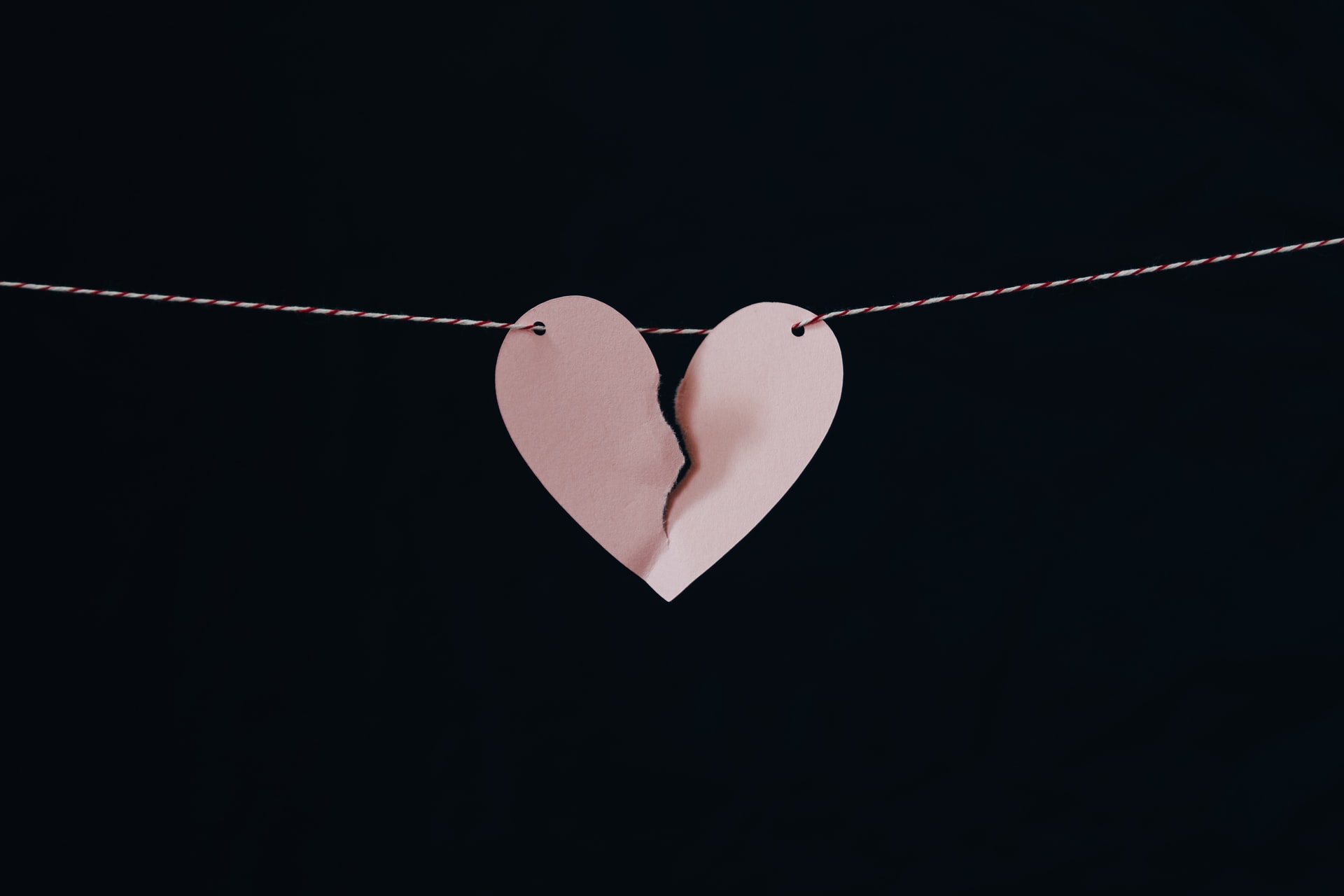 A broken pink paper heart hanging on a clothesline