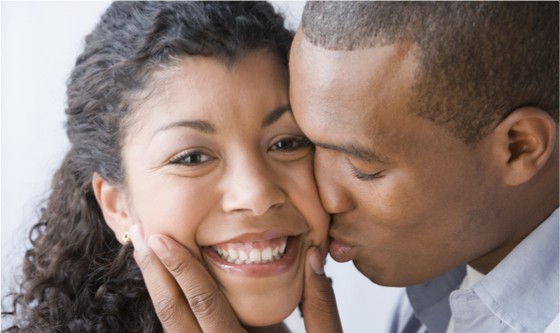Man intimately kissing a smiling woman