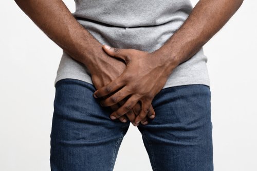 black man holding his groin over white background