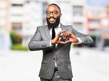 main in suit making heart sign with hands