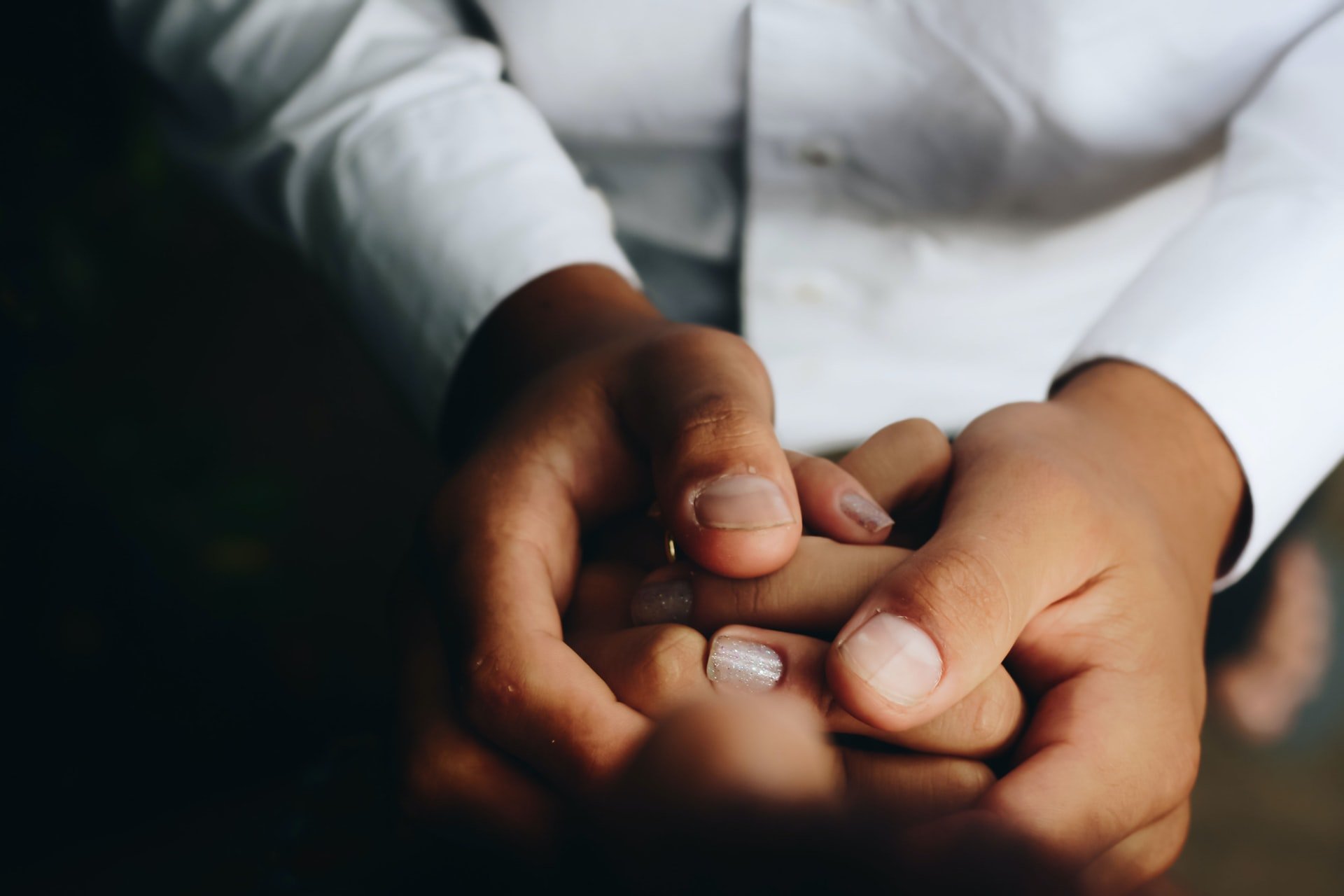 Two people's hands, holding each other