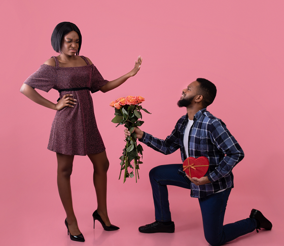 Man on his knee holding flowers is rejected by woman