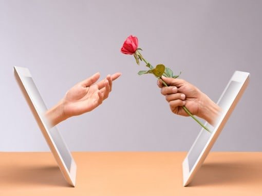 Online dating - handing a red rose out of the tablet screen