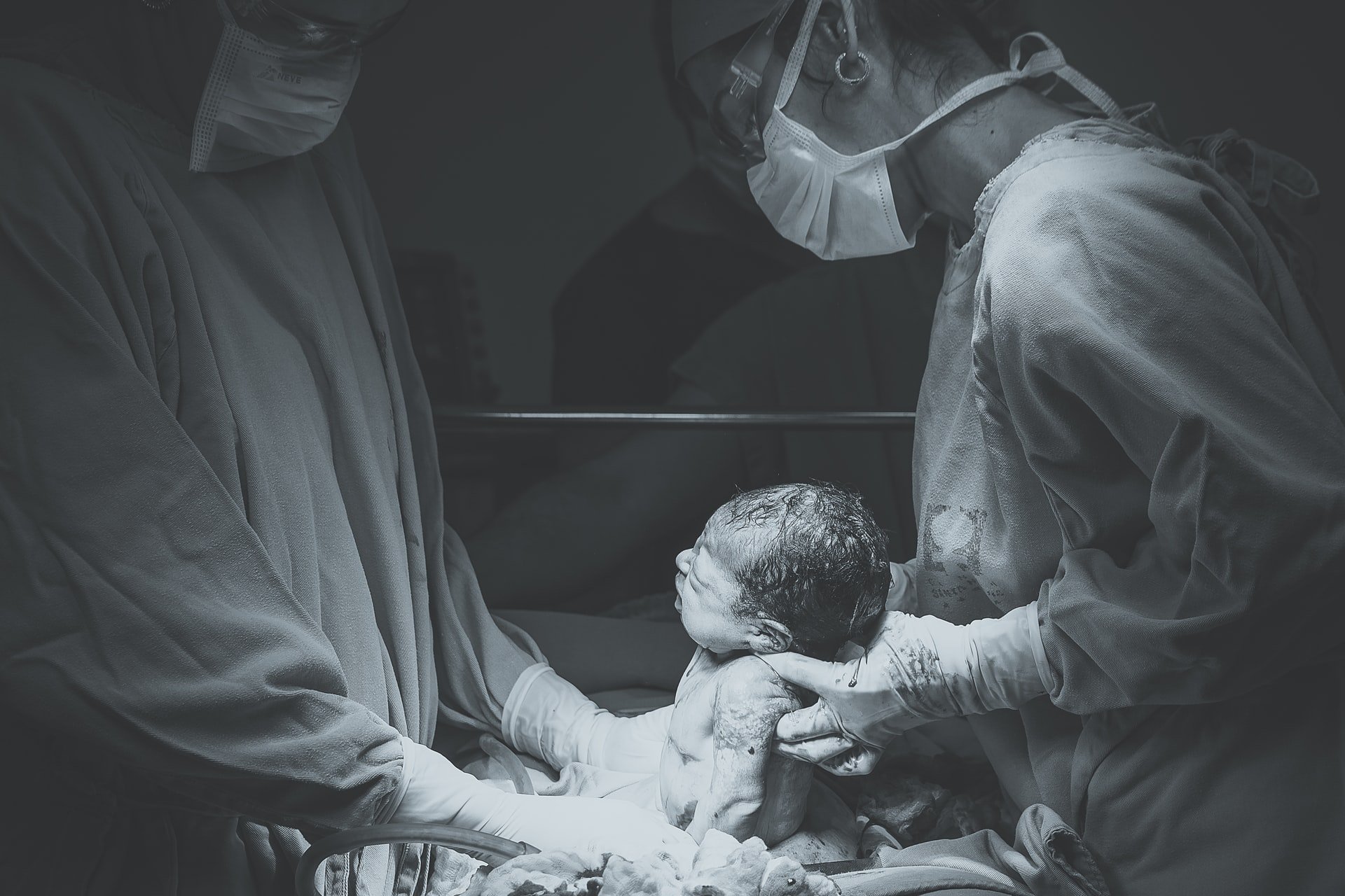 Two doctors holding a recently delivered baby between them