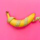 Yellow banana with measurement tape on pink background