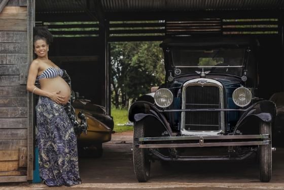 Pregnant women leaning on a wall and holding her bare tummy 