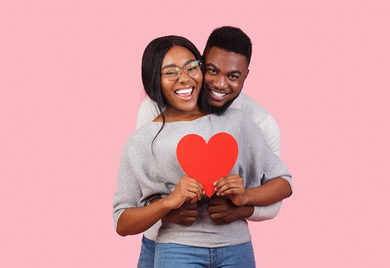 Happy heterosexual couple holding a red loved-shaped paper