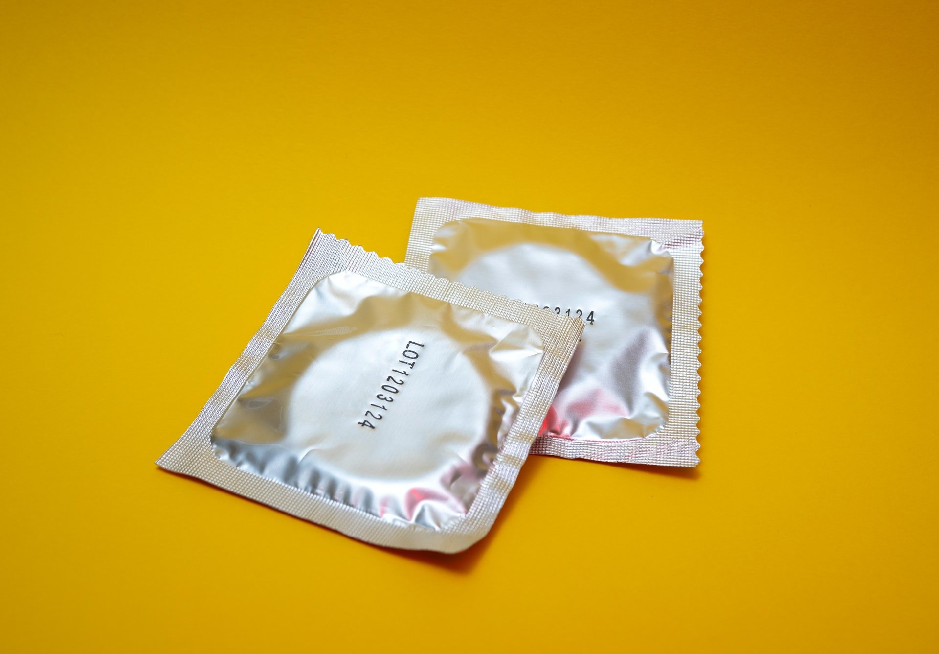 Two condoms on a yellow background