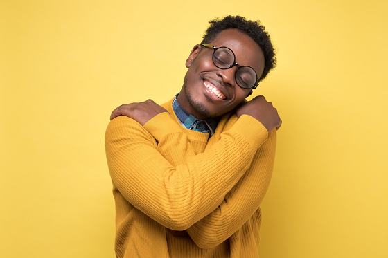 happy man in yellow sweater hugging himself