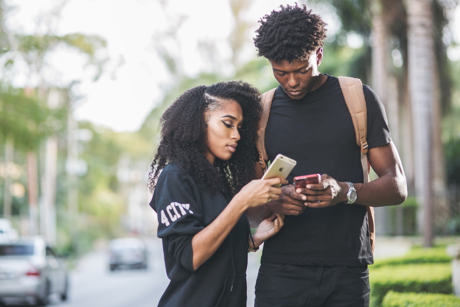 A boy and girl texting each other in the street