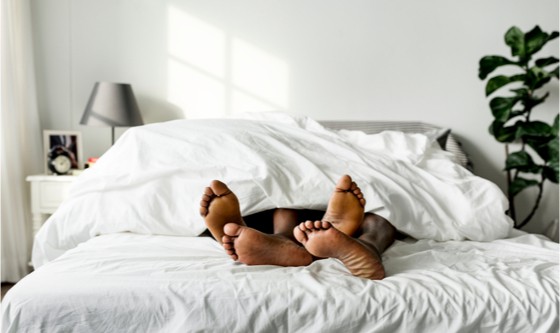 Couple in bed; the only thing visible are their feet